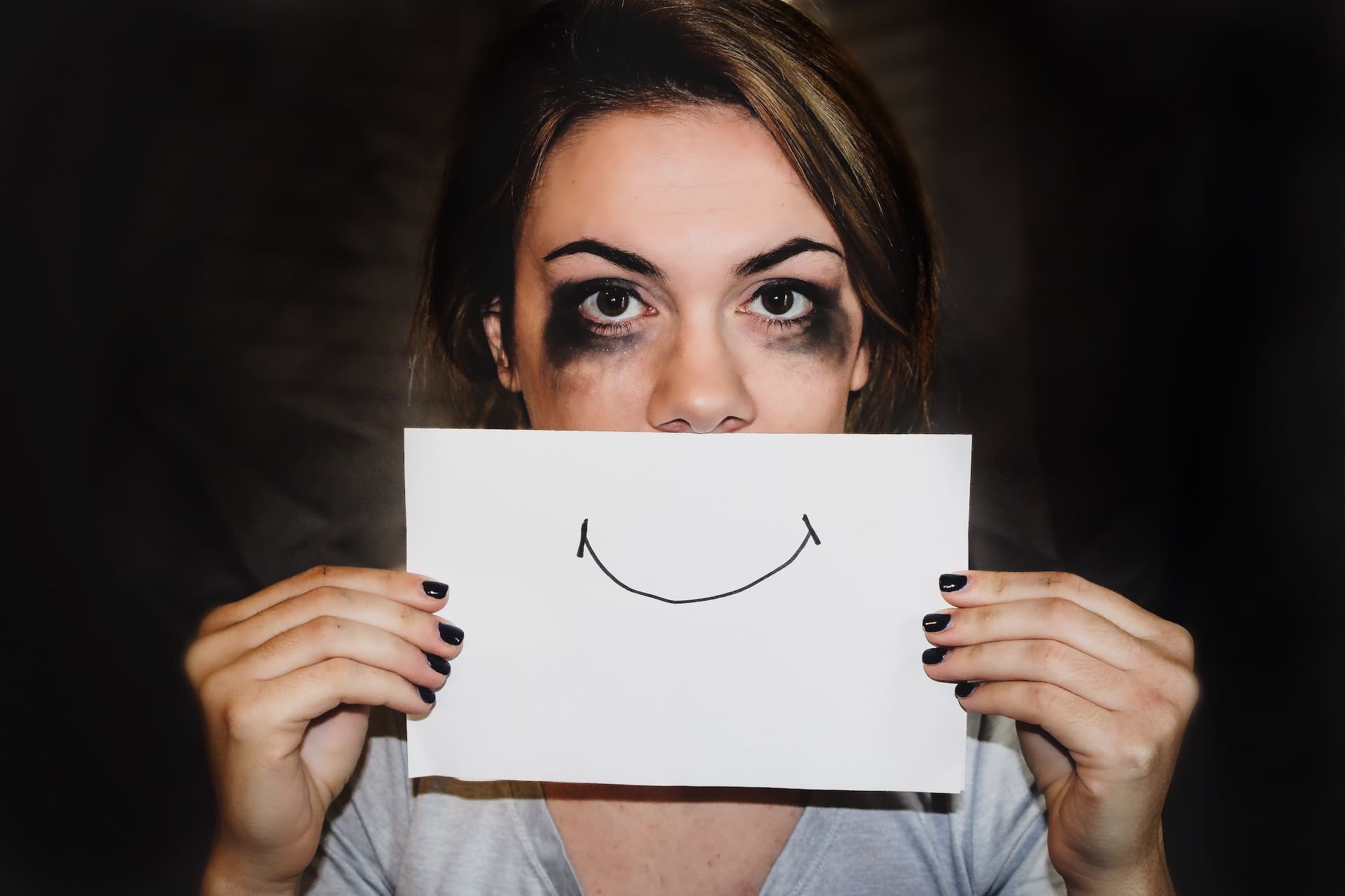 Mujer llorando con un papel con una sonrisa dibujada